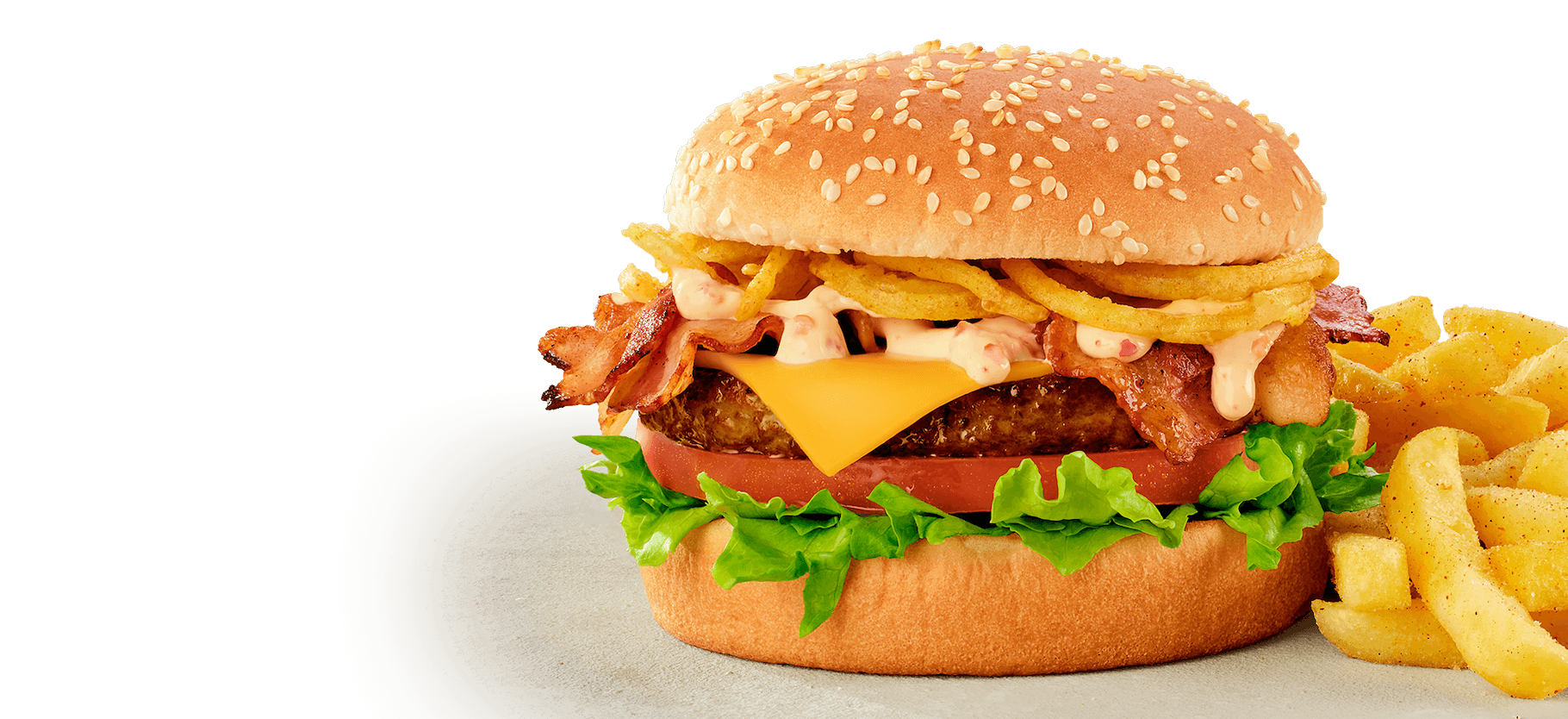Loaded bacon cheeseburger with sesame seed bun, featuring grilled beef patty, crispy bacon, melted cheddar cheese, fresh lettuce, tomato, creamy sauce, and crunchy onion rings, served with seasoned chips