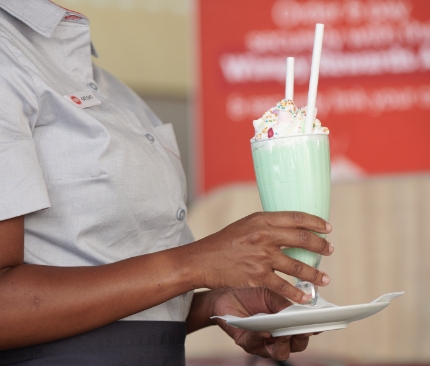 Waitron carrying a milkshake on a tray